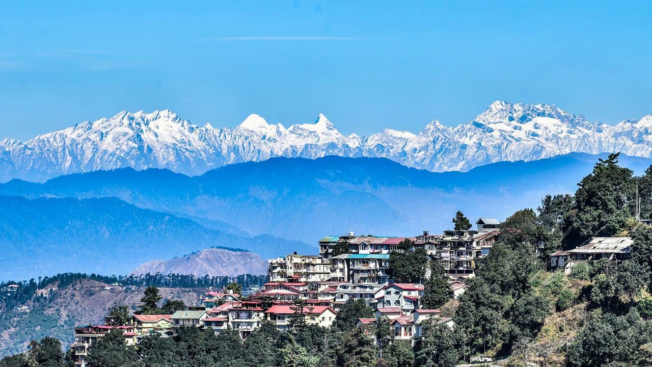 Scenic Himachal valley with snow-capped mountains and lush greenery.
